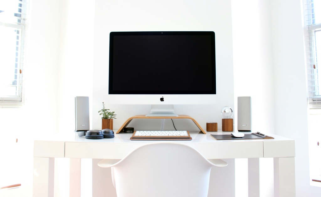 A modern white interior with a desk with a computer and two speakers on either side